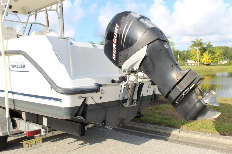 Slide: The Image of 2005 Boston Whaler 255 Conquest with Mercury outboard motor on trailer by a lake. - 9