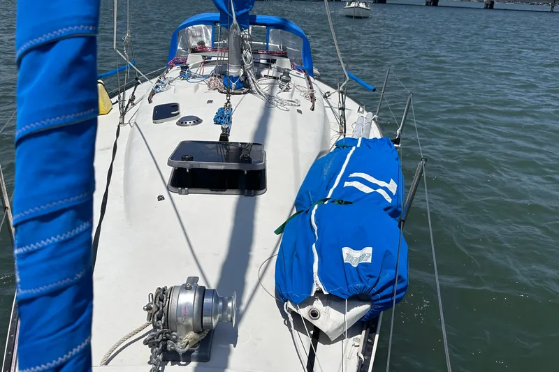 Slide: The Image of 1982 C&C 34 sailboat deck with blue sail covers on calm water. - 3