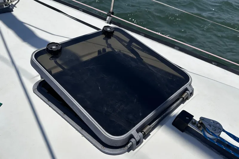 Slide: The Image of Hatch on 1982 C&C 34 sailboat deck, partially open, with ocean in background. - 7