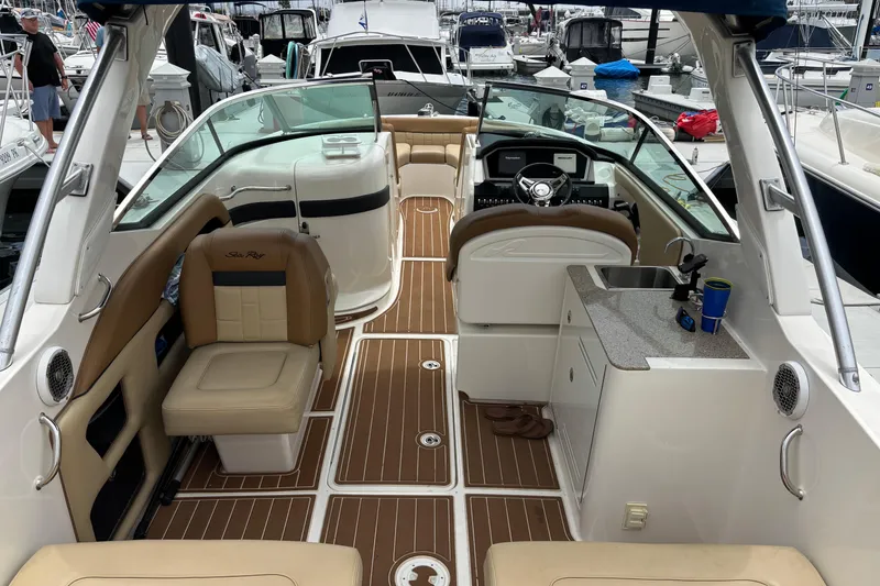 Slide: The Image of 2015 Sea Ray 300 SLX boat interior with seating, helm, and kitchenette at marina. - 4