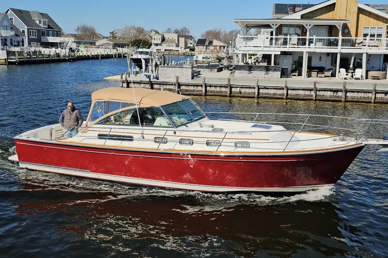 The Image of 2000 Sabreline 36 Express boat cruising near waterfront homes. - 1