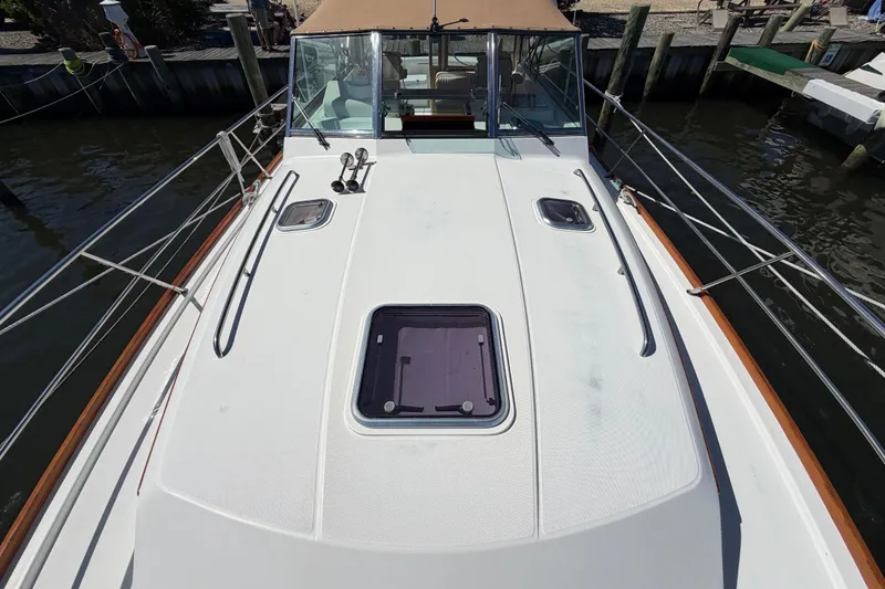 Slide: The Image of 2000 Sabreline 36 Express boat deck with hatch and railing, docked by the water. - 34