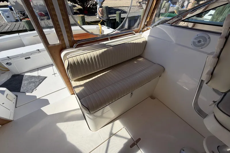 Slide: The Image of Interior seating of a 2000 Sabreline 36 Express boat, featuring beige cushioned bench. - 11