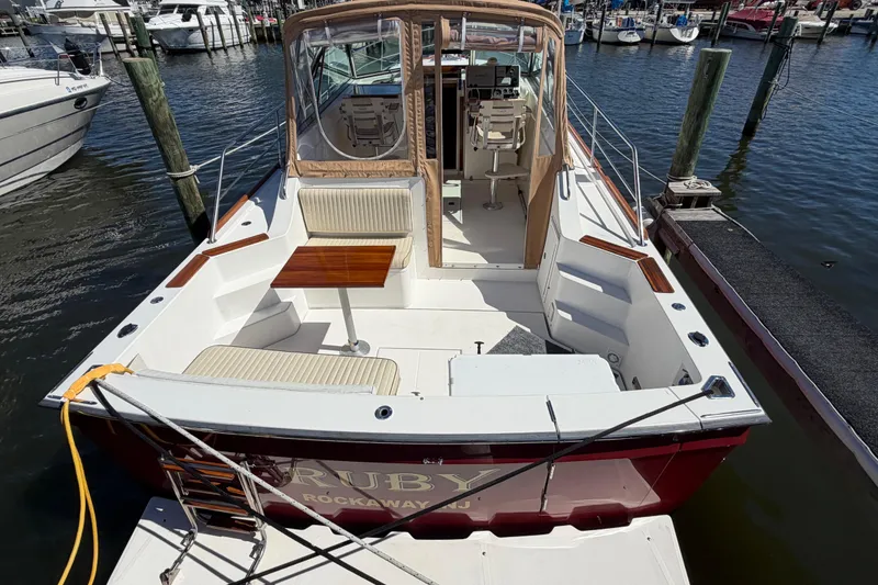 Slide: The Image of 2000 Sabreline 36 Express boat docked at marina, featuring spacious seating and table. - 5