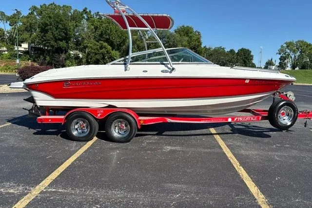 Slide: The Image of 2003 Crownline 208 LX boat in red and white on a trailer, parked outdoors. - 9