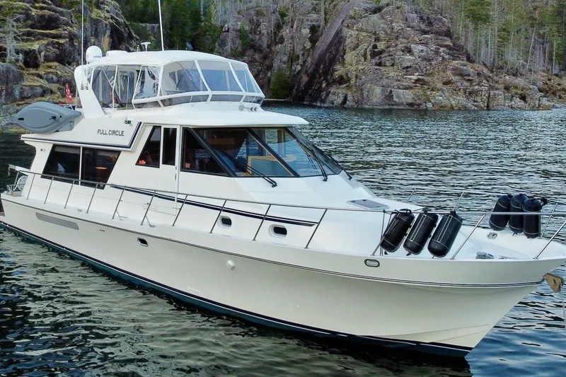 The Image of 2002 Canoe Cove 50 Pilothouse Luxury Yacht on scenic waterway with rocky shoreline. - 0