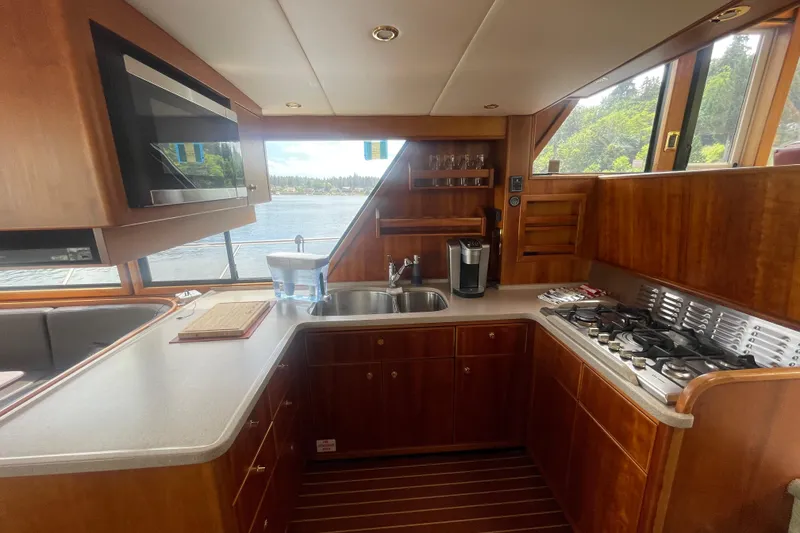Slide: The Image of Luxurious kitchen interior of 2002 Canoe Cove 50 Pilothouse Yacht with wood cabinetry and modern appliances. - 19