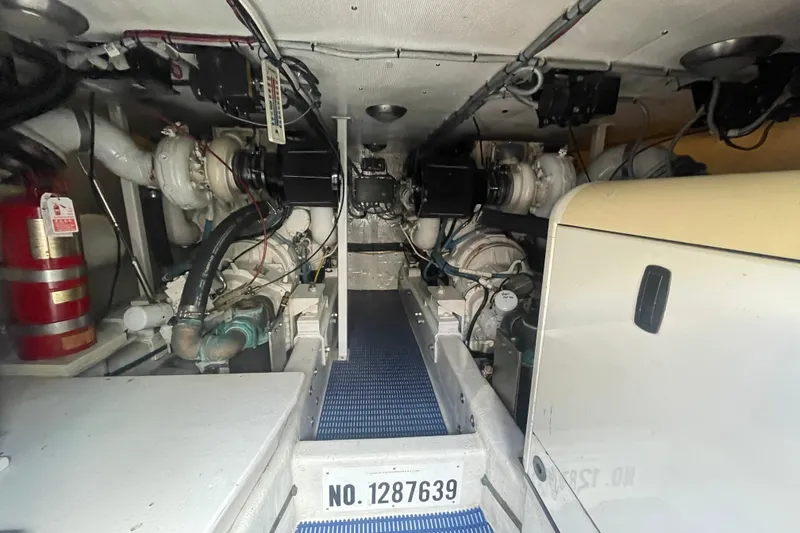 Slide: The Image of Engine room of 2002 Canoe Cove 50 Pilothouse Luxury Yacht, featuring mechanical components and fire extinguisher. - 56