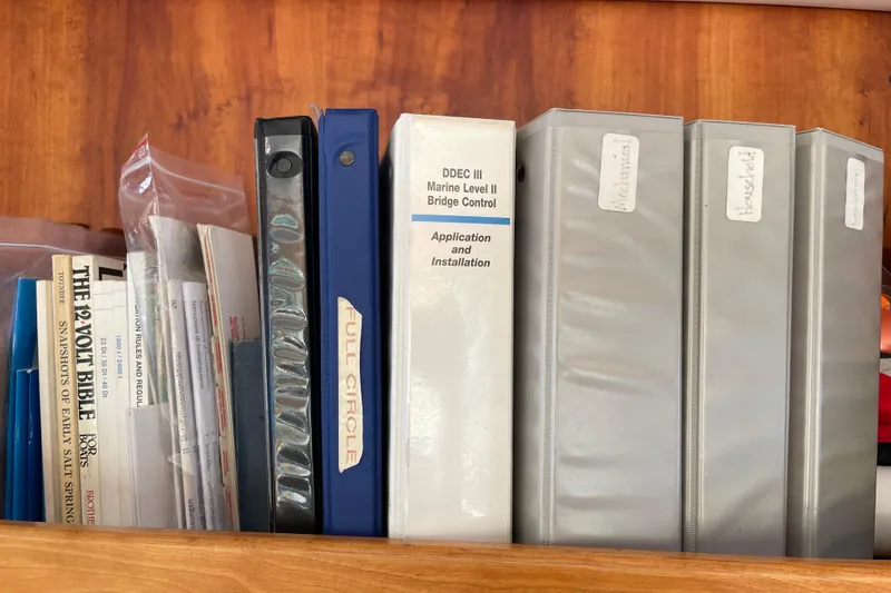 Slide: The Image of Binders and manuals on a shelf, including marine installation guides for a 2002 Canoe Cove yacht. - 66