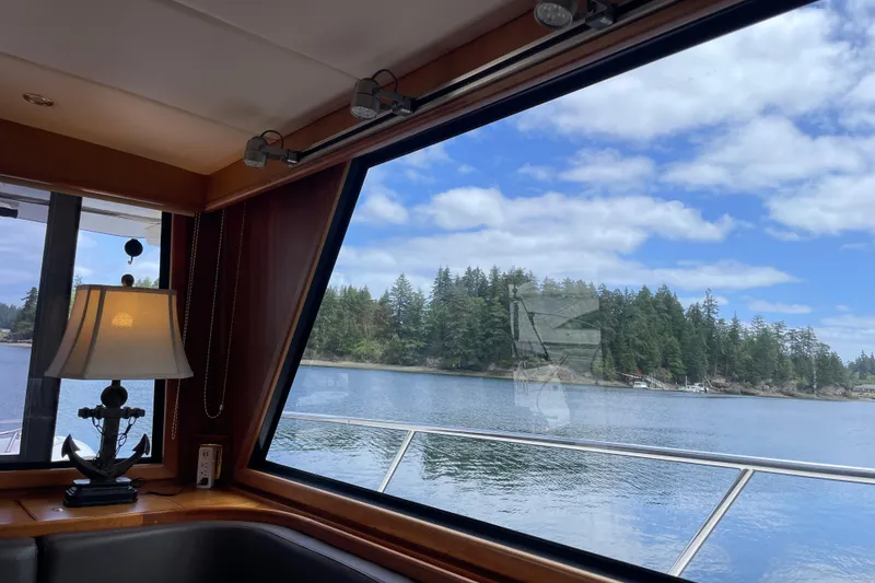 Slide: The Image of Interior view from 2002 Canoe Cove 50 Pilothouse Yacht, overlooking serene waters and lush forest. - 67