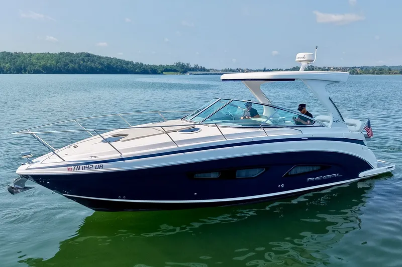 Slide: The Image of 2021 Regal 33 Express boat cruising on a serene lake with passengers onboard. - 78