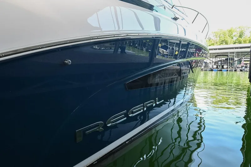 Slide: The Image of 2021 Regal 33 Express yacht docked on calm water, reflecting marina surroundings. - 5