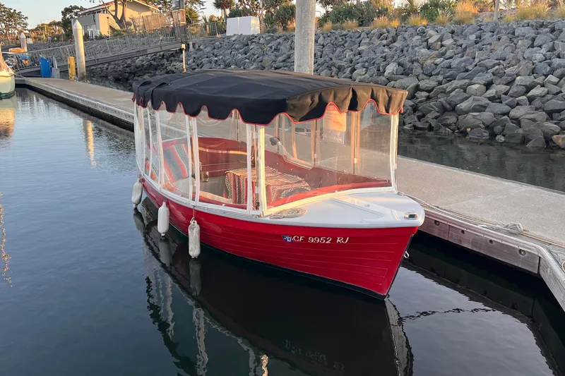 Slide: The Image of Red 2007 Duffy 16 boat docked, featuring a black canopy and clear side panels. - 4