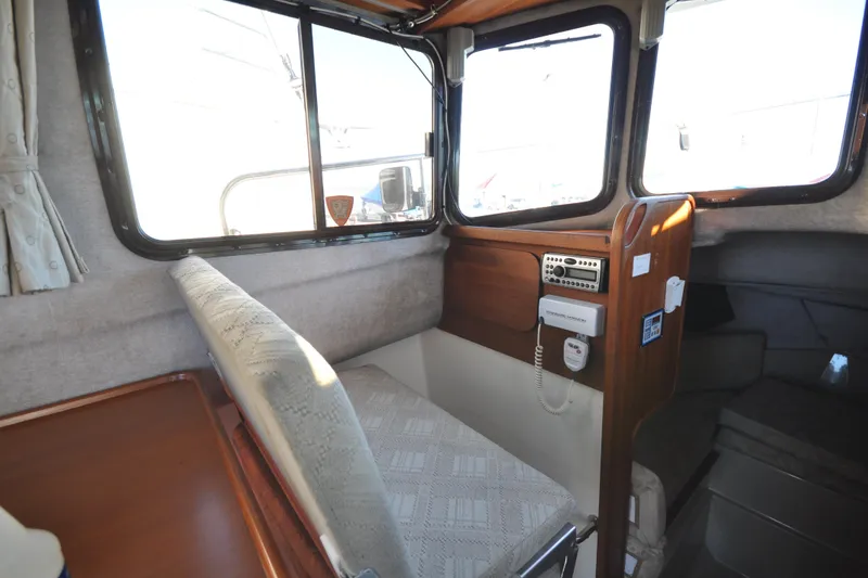 Slide: The Image of Interior of a 2007 Ranger Tug R-25 boat, featuring a cozy seating area and control panel. - 12