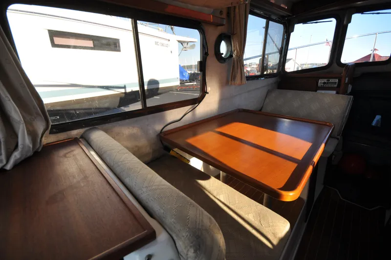 Slide: The Image of Interior of 2007 Ranger Tug R-25, featuring a cozy dining area with wooden table. - 25