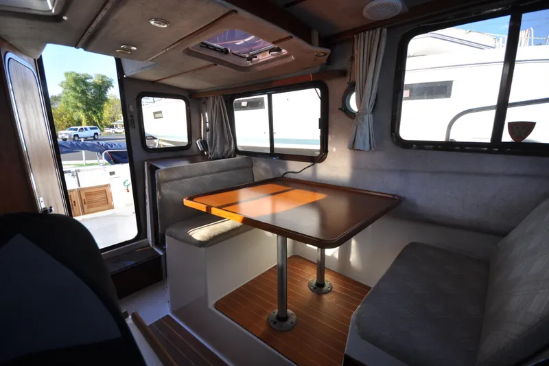 Slide: The Image of Interior of 2007 Ranger Tug R-25, featuring a cozy dining area with wooden table. - 27
