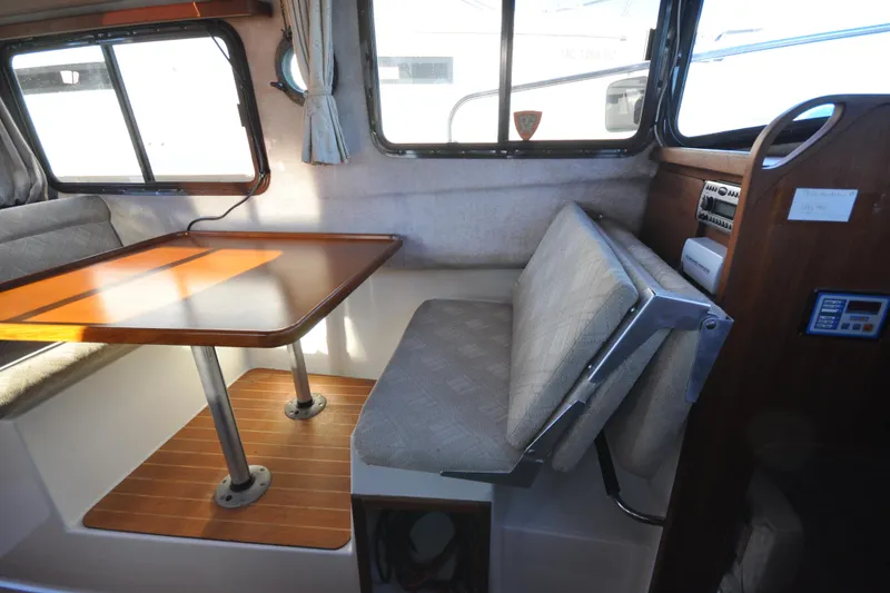Slide: The Image of Interior of 2007 Ranger Tug R-25, featuring a cozy dining area with wooden table. - 28