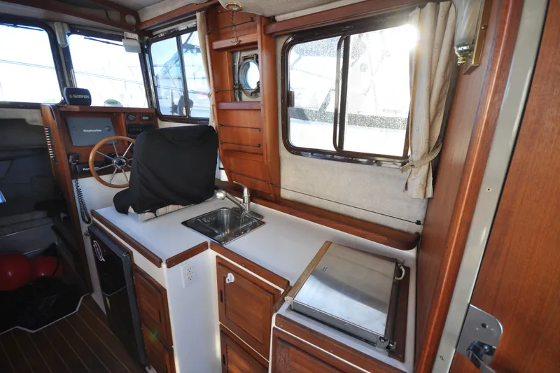 Slide: The Image of Interior of 2007 Ranger Tug R-25 boat with helm, sink, and wooden cabinetry. - 9