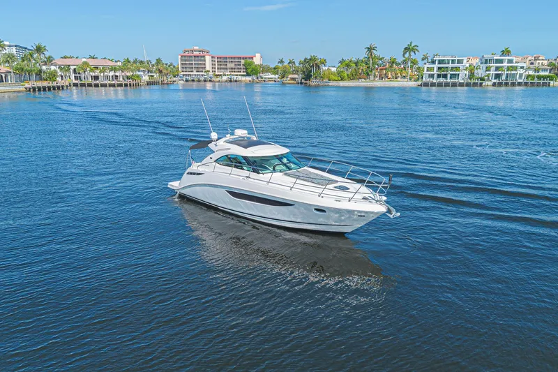 Slide: The Image of 2014 Sea Ray 410 Sundancer yacht cruising on a sunny day in a scenic waterfront area. - 10