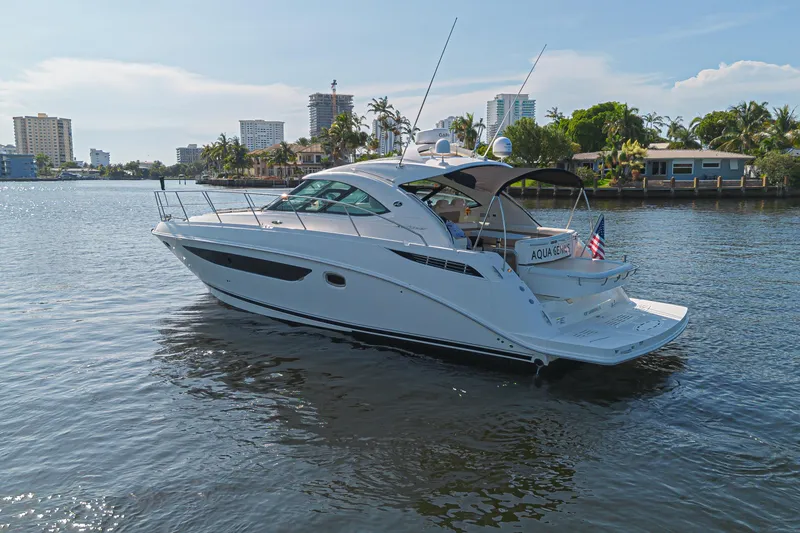 Slide: The Image of 2014 Sea Ray 410 Sundancer yacht cruising on a sunny waterfront with cityscape background. - 3