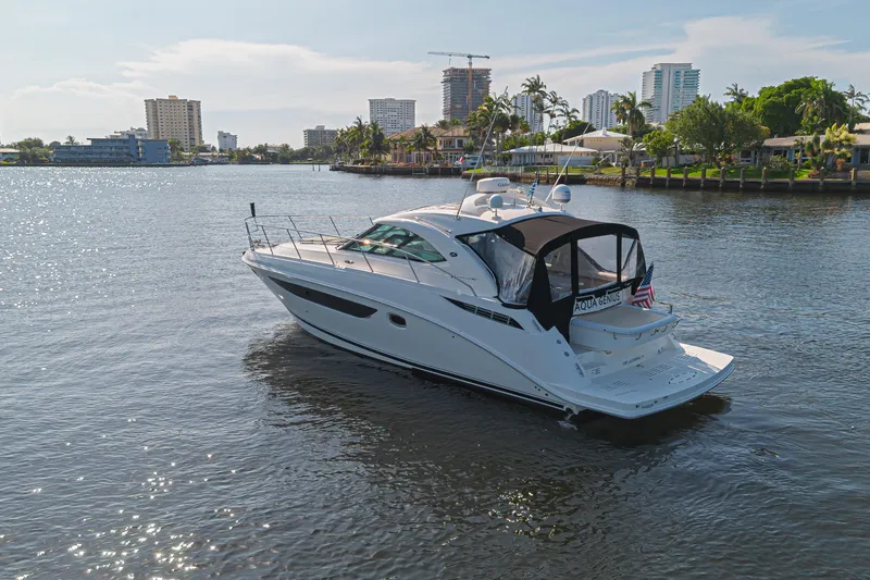 Slide: The Image of 2014 Sea Ray 410 Sundancer yacht cruising on a sunny waterfront with cityscape background. - 4