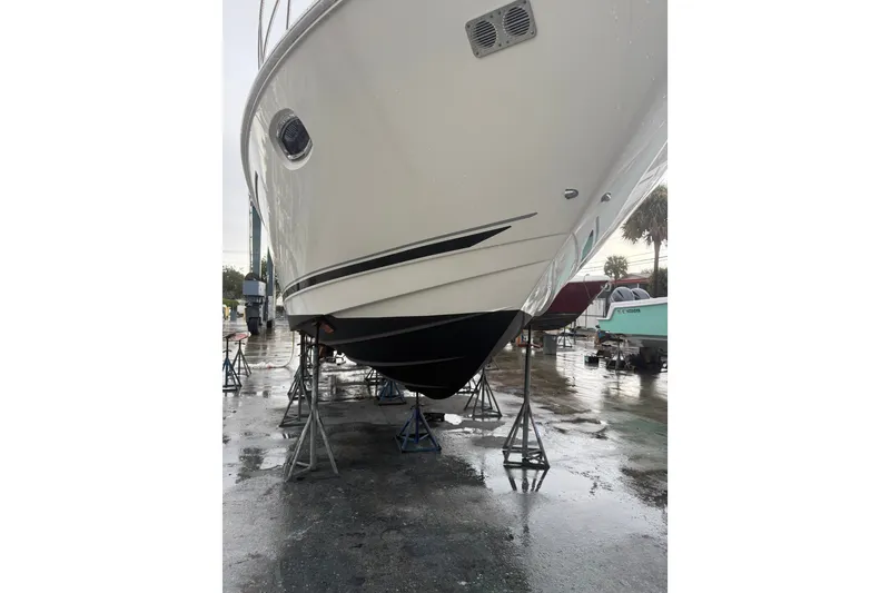 Slide: The Image of 2014 Sea Ray 410 Sundancer yacht on stands in a marina, showcasing its sleek hull design. - 38
