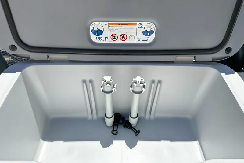 Slide: The Image of Open storage compartment of 2026 Sea-Doo Switch Fish 21, featuring interior components and warning label. - 17