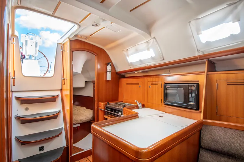 Slide: The Image of Interior of a Beneteau 343 yacht with a kitchen and stairs leading to a hatch. - 12