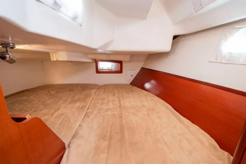 Slide: The Image of Interior of a sailboat with a large bed and wood paneling. - 21