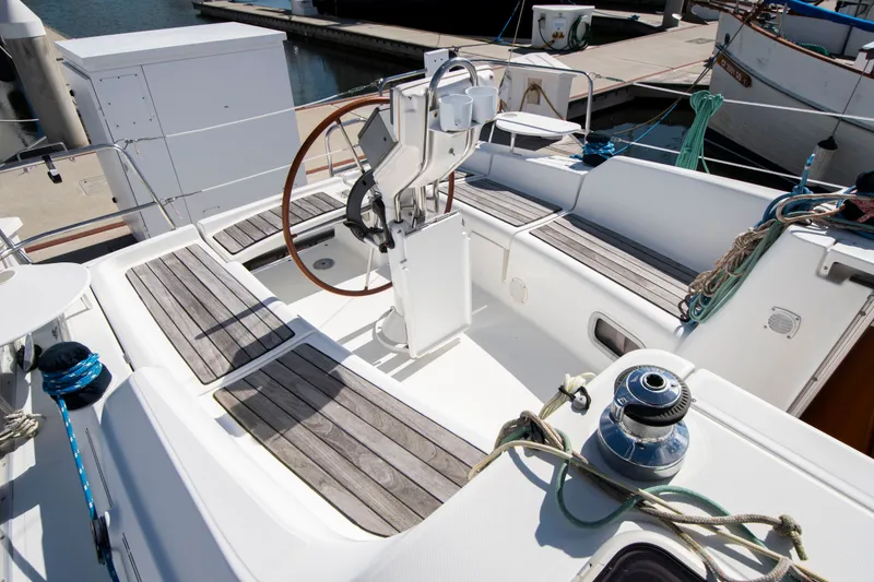Slide: The Image of The cockpit of a Beneteau 343 yacht with wooden seats and a steering wheel in a marina. - 8