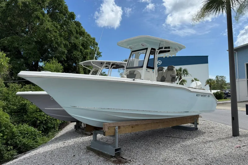 The Image of 2026 Key West 239 FS boat displayed outdoors on gravel, under a clear blue sky. - 0