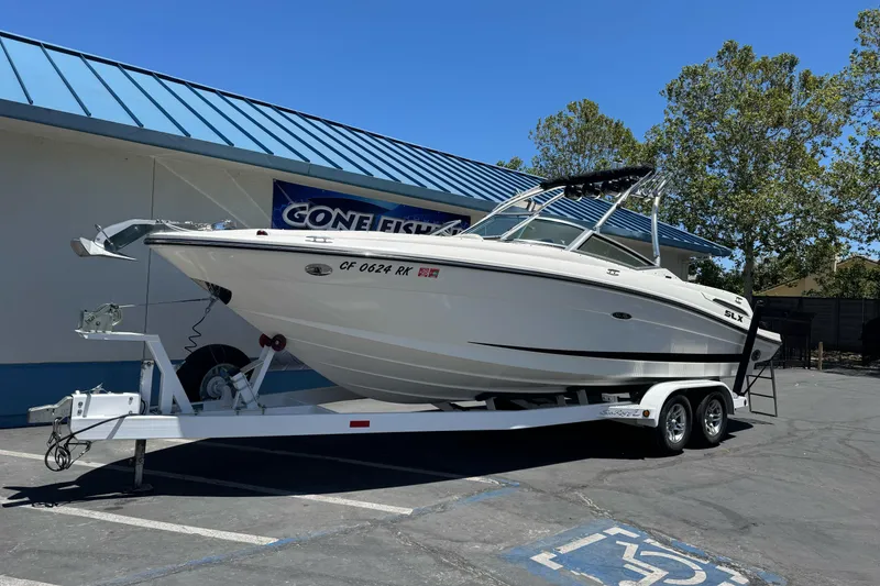 Slide: The Image of 2007 Sea Ray SLX 250 boat on trailer, parked outdoors near a building. - 1
