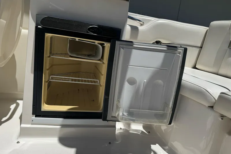 Slide: The Image of Open mini fridge on 2007 Sea Ray SLX 250 boat, showcasing interior shelves and seating area. - 21