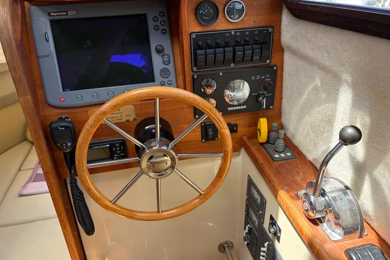 Slide: The Image of 2008 Ranger Tugs R-25 helm with wooden steering wheel and navigation controls. - 10