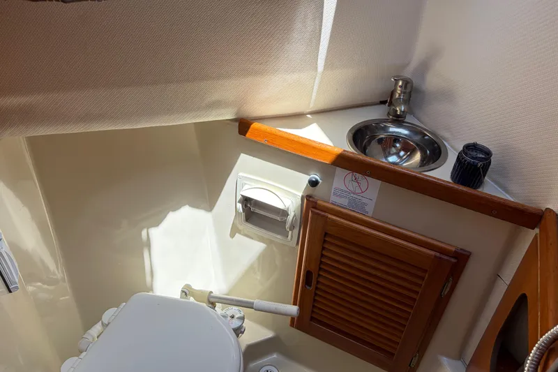 Slide: The Image of Compact bathroom in 2008 Ranger Tugs R-25 boat with sink and wooden cabinet. - 12