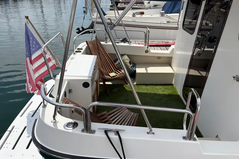 Slide: The Image of 2008 Ranger Tugs R-25 boat with American flag, wooden chairs, and artificial grass deck. - 6