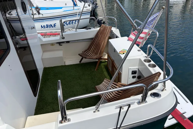 Slide: The Image of 2008 Ranger Tugs R-25 boat deck with chairs, American flag, and marina view. - 7