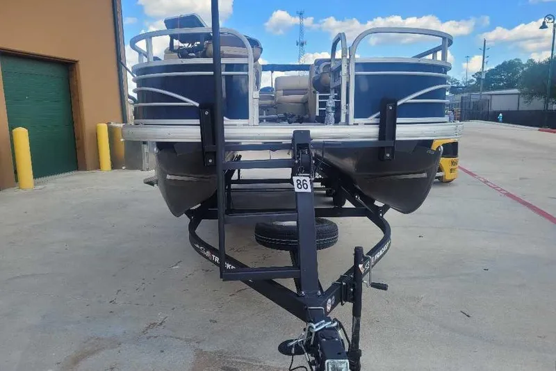 Slide: The Image of 2022 Sun Tracker Fishin' Barge 22 DLX pontoon boat on trailer, outdoor setting. - 3