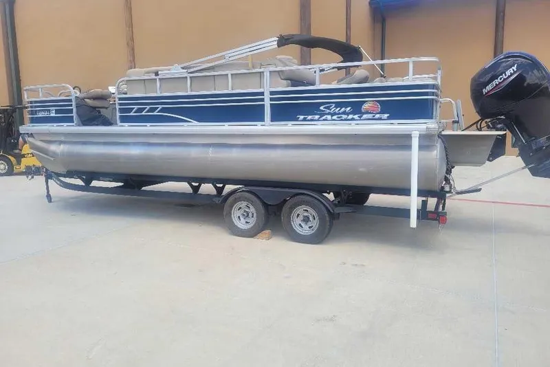 Slide: The Image of 2022 Sun Tracker Fishin' Barge 22 DLX pontoon boat on trailer in storage facility. - 6