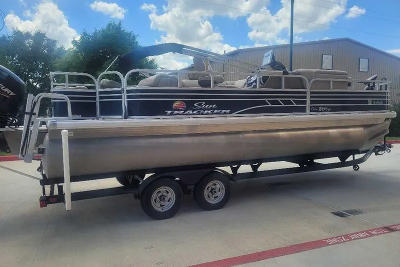 Slide: The Image of 2022 Sun Tracker Fishin' Barge 22 DLX pontoon boat on trailer, outdoors. - 7