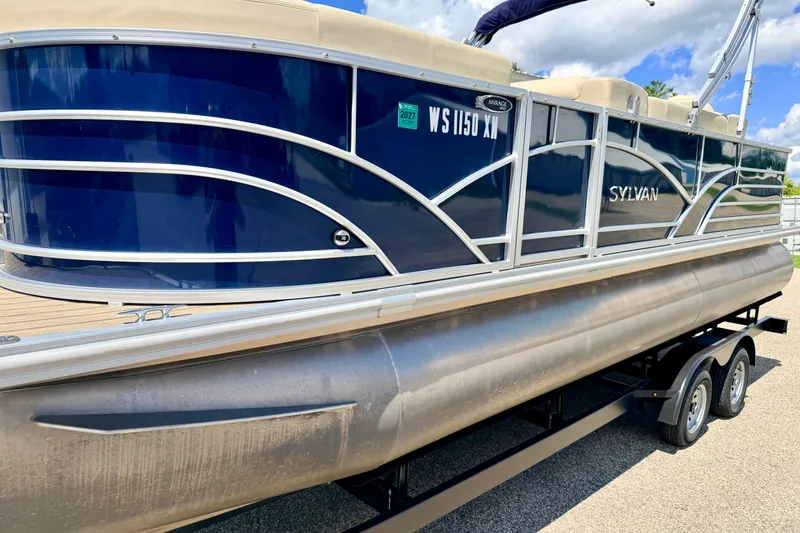 Slide: The Image of 2018 Sylvan 8522 Mirage Fish pontoon boat on trailer, blue and beige exterior. - 12