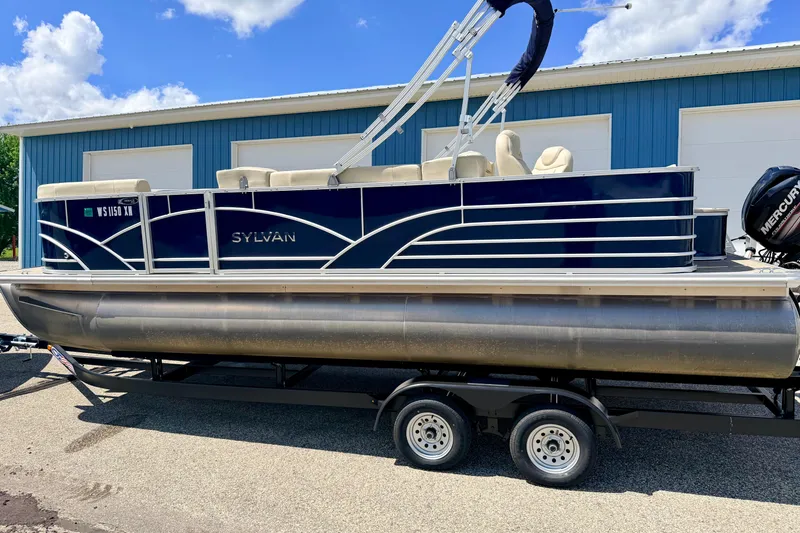 Slide: The Image of 2018 Sylvan 8522 Mirage Fish pontoon boat on trailer, parked near blue building. - 4