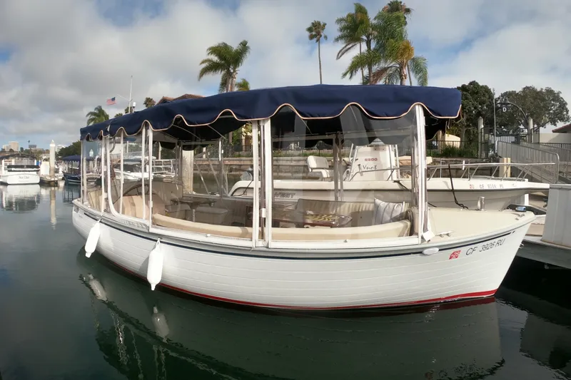 The Image of 2008 Duffy Snug Harbor 18 electric boat docked, featuring a blue canopy and clear side panels. - 0