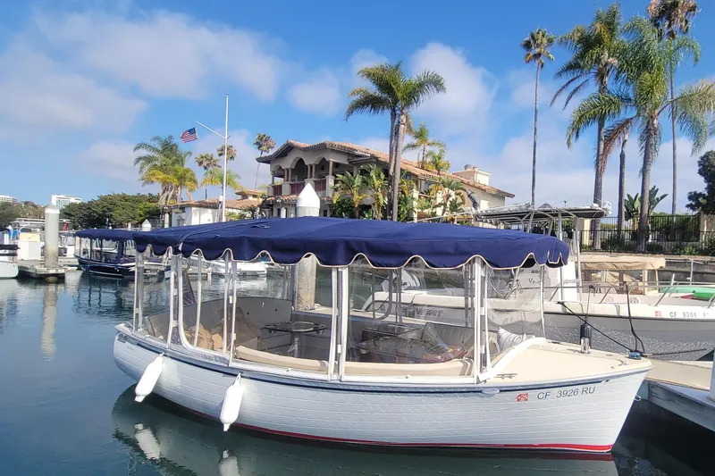 Slide: The Image of 2008 Duffy Snug Harbor 18 boat docked, featuring blue canopy and scenic waterfront backdrop. - 9