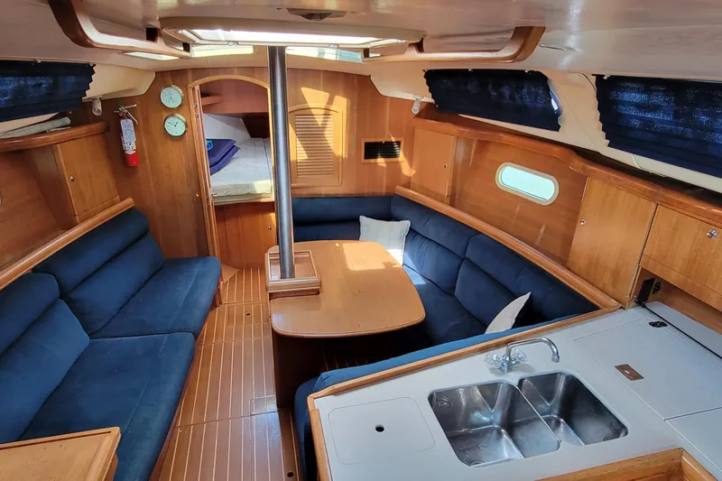 Slide: The Image of Interior of a 2002 Hunter 356 sailboat with blue seating and wooden finishes. - 4