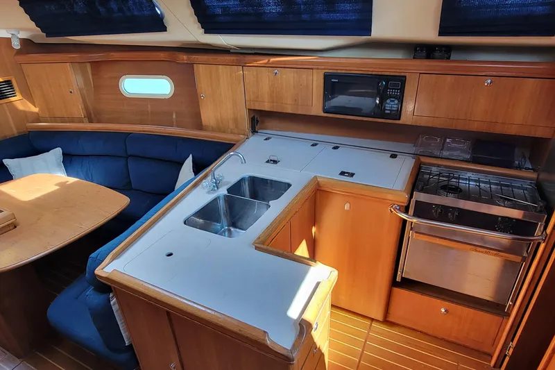 Slide: The Image of Interior of a 2002 Hunter 356 yacht featuring a cozy kitchen and dining area. - 5