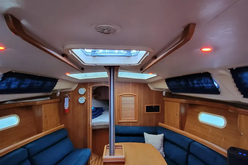 Slide: The Image of Interior of 2002 Hunter 356 sailboat with wood finish and blue seating. - 6