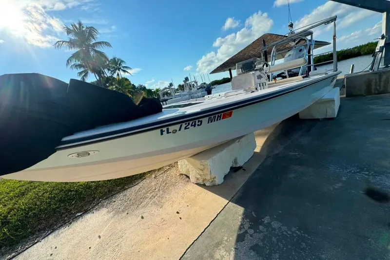 Slide: The Image of 2003 Hewes Redfisher 21 boat on blocks, sunny day, palm trees in background. - 2