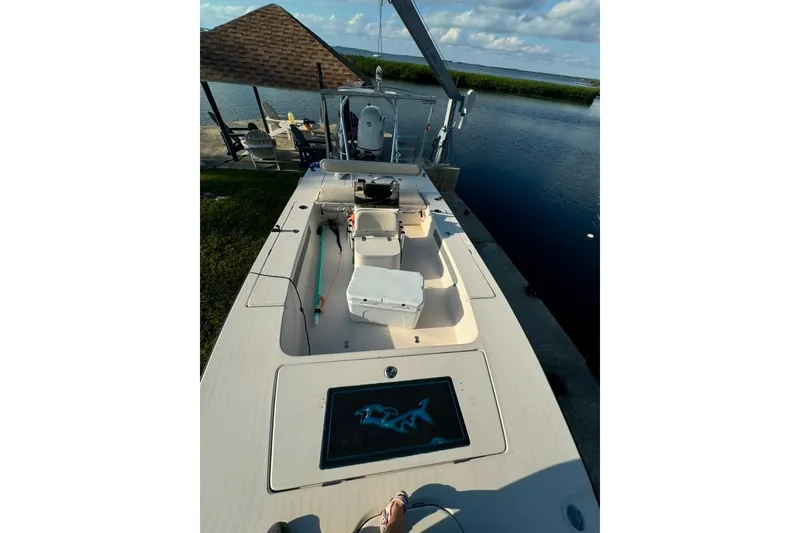 Slide: The Image of 2003 Hewes Redfisher 21 boat docked by a serene waterfront under a blue sky. - 3