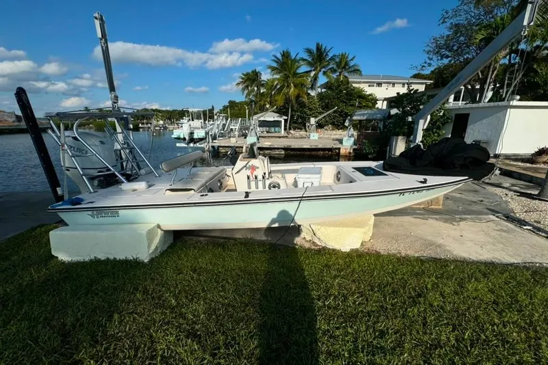Slide: The Image of 2003 Hewes Redfisher 21 boat docked by a scenic waterfront with palm trees. - 4